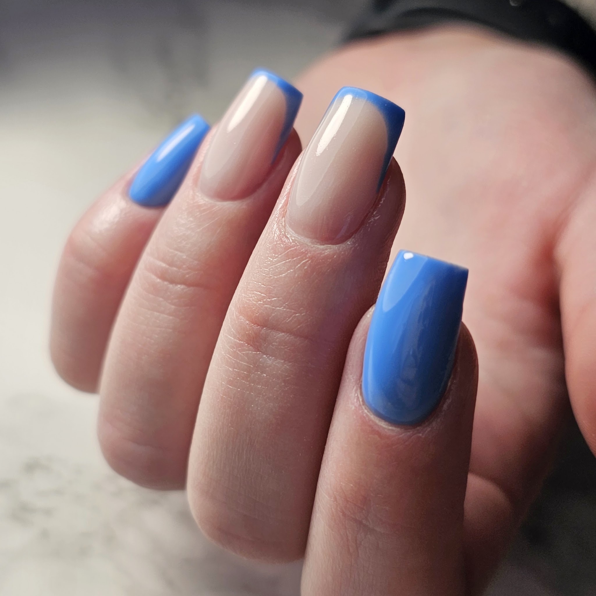 Vierkante nude nagels met een blauwe French en twee nagels helemaal in het blauw